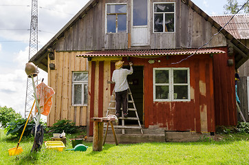 Image showing Painter man on ladder paint old wooden house 