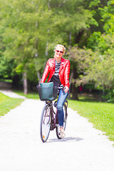 Image showing Young woman riding a bicycle.