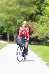 Image showing Young woman riding a bicycle.