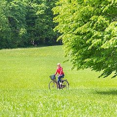 Image showing Young woman riding a bicycle.