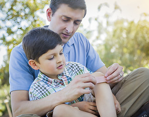 Image showing Loving Father Puts Bandage on Knee of Young Son