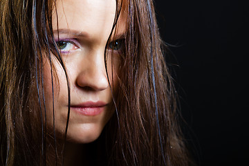 Image showing portrait of a sad young girl with long wet hair on a black