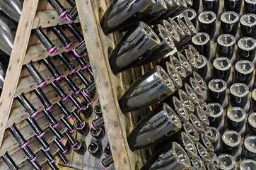 Image showing Dusty bottles with brut sparkling wine on wooden rack