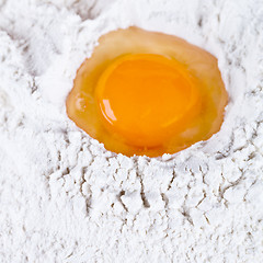 Image showing broken egg on flour