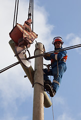 Image showing electrician raises the wire on top of an electricity pylon 