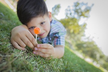 Image showing Young Boy Enjoying His Lollipop Outdoors Laying on Grass