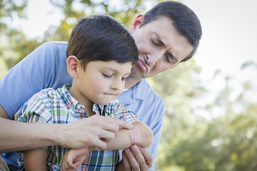 Image showing Loving Father Puts Bandage on Elbow of Young Son