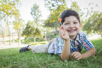 Image showing Young Boy Enjoying His Lollipop Outdoors Laying on Grass