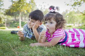 Image showing Young Brother and Baby Sister Enjoying Their Lollipops Outdoors