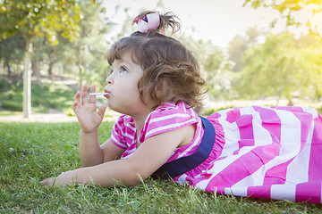 Image showing Cute Baby Girl Enjoying Lollipop Outdoors