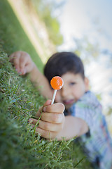 Image showing Young Boy Enjoying His Lollipop Outdoors Laying on Grass