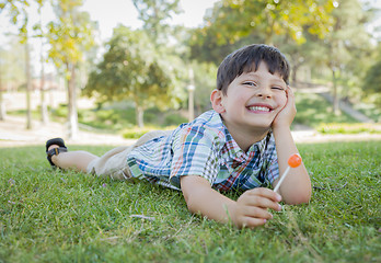 Image showing Young Boy Enjoying His Lollipop Outdoors Laying on Grass