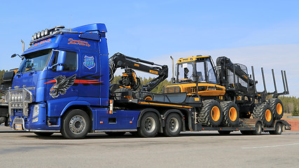 Image showing Blue Volvo FH13 Truck Hauling Ponsse Forestry Machinery