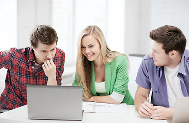 Image showing smiling students looking at laptop at school