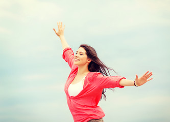 Image showing girl with hands up on the beach