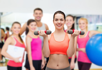 Image showing young sporty woman with light dumbbells