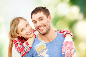 Image showing smiling couple covered with paint with paint brush