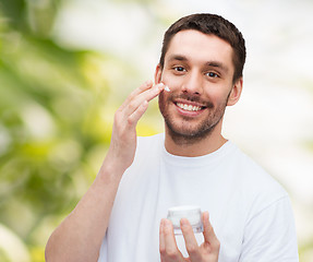 Image showing beautiful smiling man applyin cream