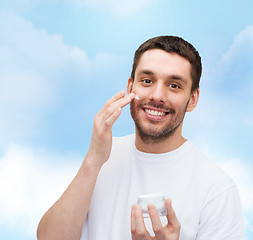 Image showing beautiful smiling man applyin cream