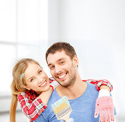 Image showing smiling couple covered with paint with paint brush