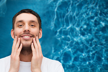 Image showing beautiful smiling man touching his face