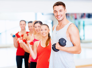 Image showing group of smiling people with dumbbells in the gym