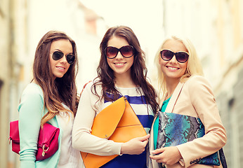 Image showing three smiling women with bags in the city