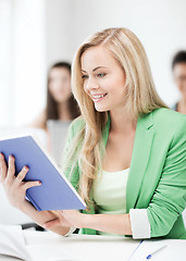 Image showing smiling young girl reading book at school