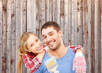 Image showing smiling couple covered with paint with paint brush