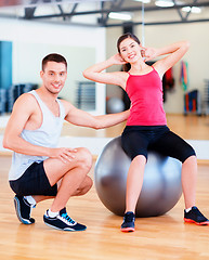 Image showing male trainer with woman doing crunches on the ball