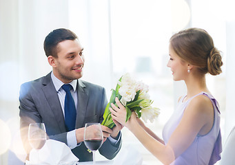 Image showing smiling man giving flower bouquet at restaurant