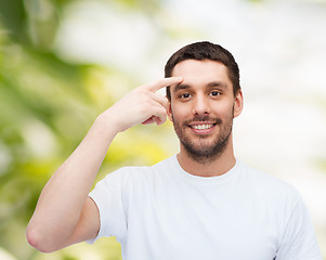 Image showing smiling young handsome man pointing to forehead