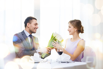 Image showing smiling man giving flower bouquet at restaurant