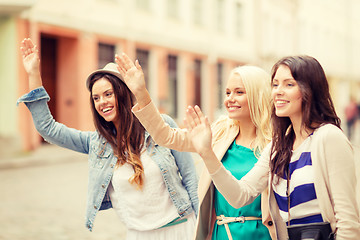 Image showing three beautiful girls waving hands