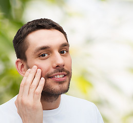 Image showing beautiful smiling man touching his face