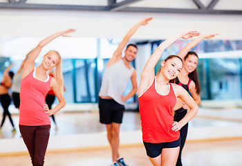 Image showing group of smiling people stretching in the gym