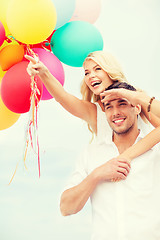 Image showing couple with colorful balloons at seaside