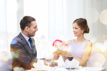 Image showing smiling man giving flower bouquet at restaurant