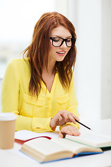 Image showing smiling student girl reading books in library