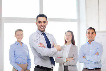 Image showing smiling businessman in office with team on back