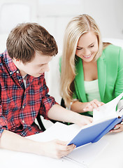 Image showing smiling students reading book at school