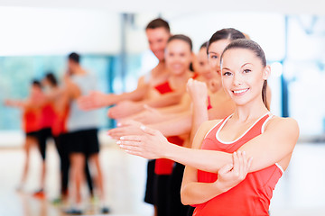 Image showing group of smiling people stretching in the gym