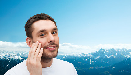 Image showing beautiful smiling man touching his face