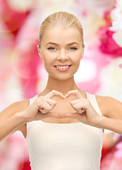 Image showing smiling young woman showing heart shape gesture