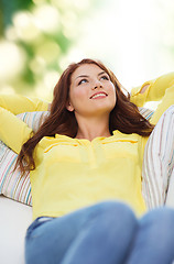 Image showing smiling young woman lying on sofa at home