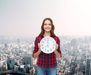Image showing young woman in casual clothes with wall clock