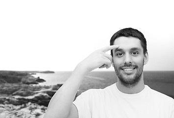 Image showing smiling young handsome man pointing to forehead