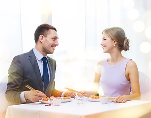 Image showing smiling couple eating sushi at restaurant