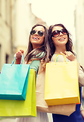 Image showing two girls in sunglasses with shopping bags in ctiy