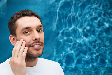 Image showing beautiful smiling man touching his face